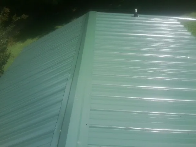New green metal panels meeting at the ridge of a roof — Flat Roof Repair work by our crew in Alfred