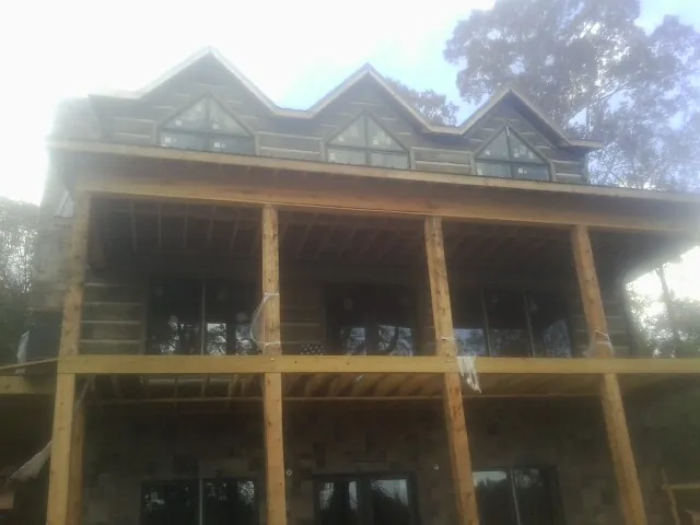 Dormers and porch framing on a large log home under construction — Roof Coating work by our crew in Alfred