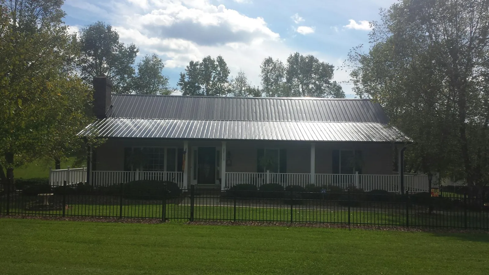 Gray metal roof on a brick ranch with a full width front porch — Gutter Guard Installation work by our crew in Alfred