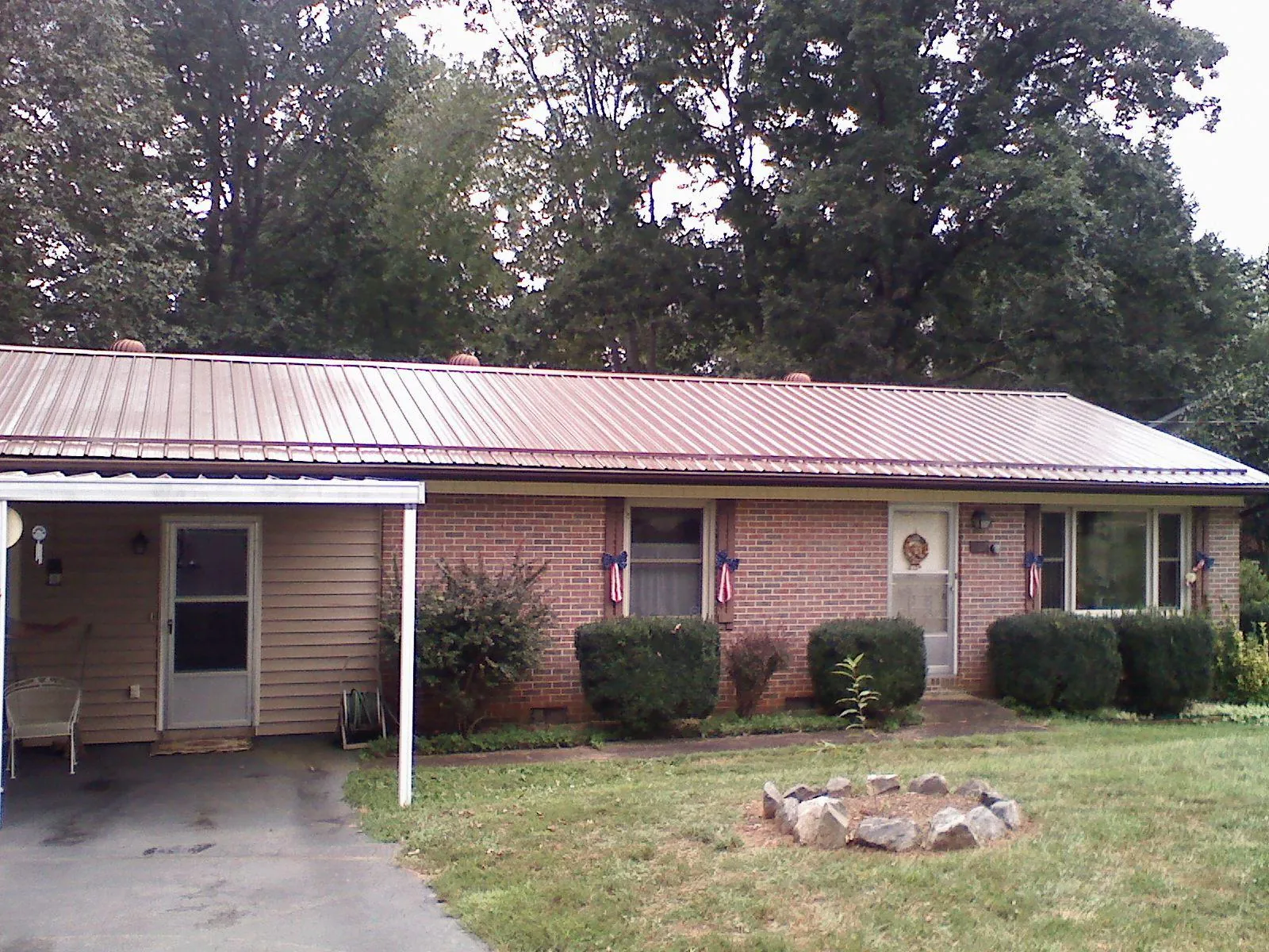 Bronze metal roof and carport on a brick ranch home — Roof Repair work by our crew in Alfred