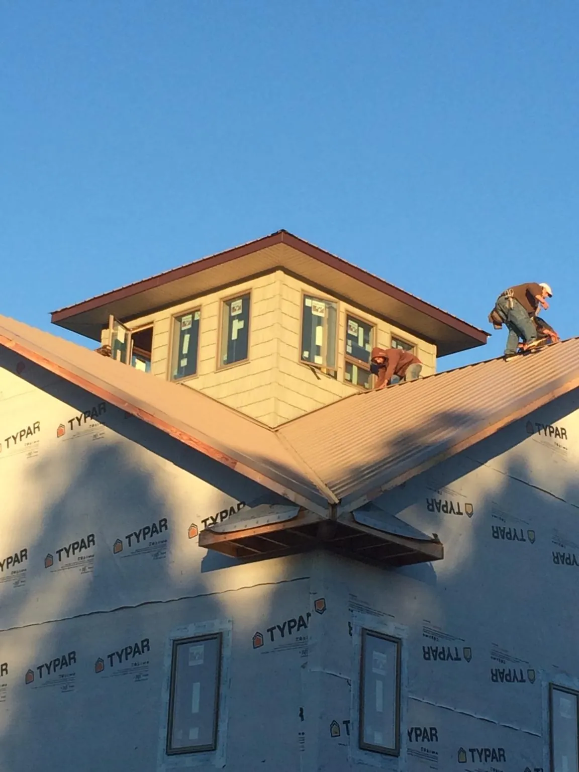 Roofers working around a rooftop cupola on a new metal roof at sunset — Roof Waterproofing in Alfred by Roofing Brothers